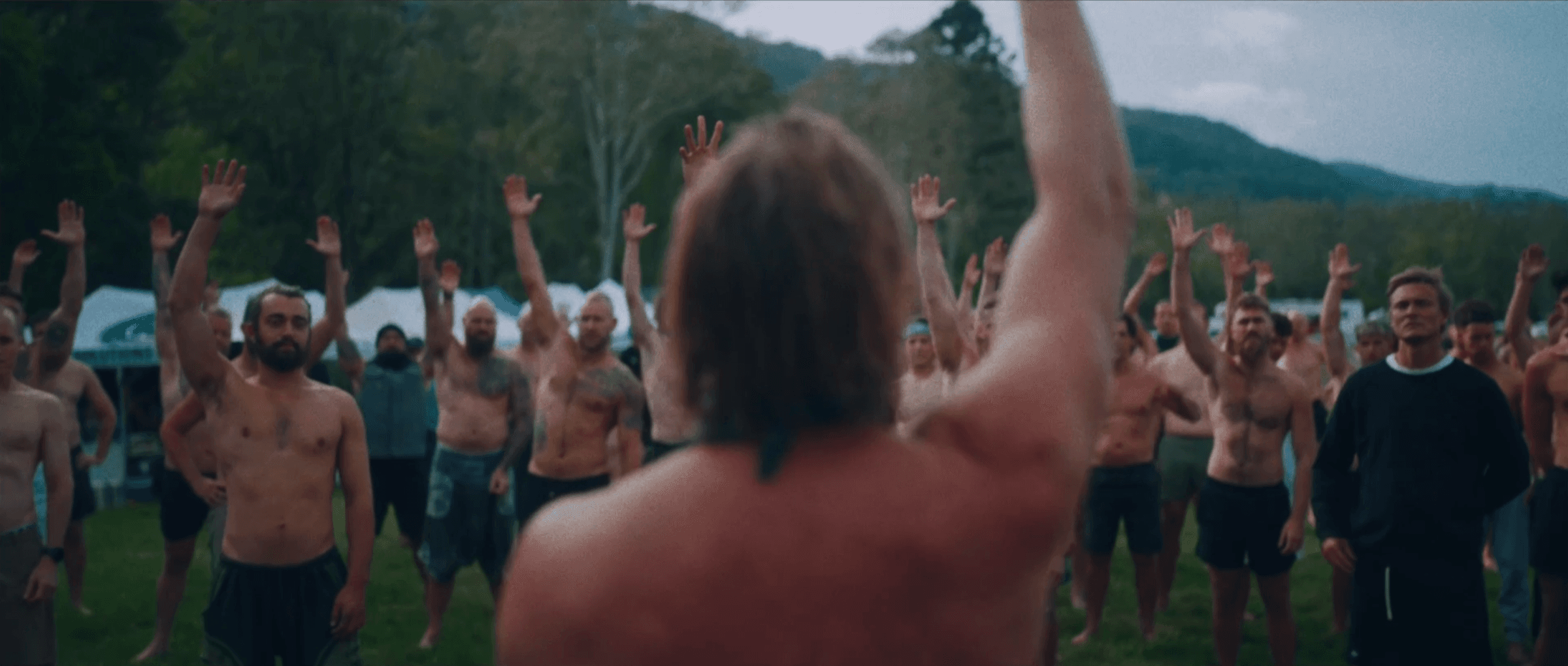 A circle of men, arms raised, at an Embodied Man Institute gathering