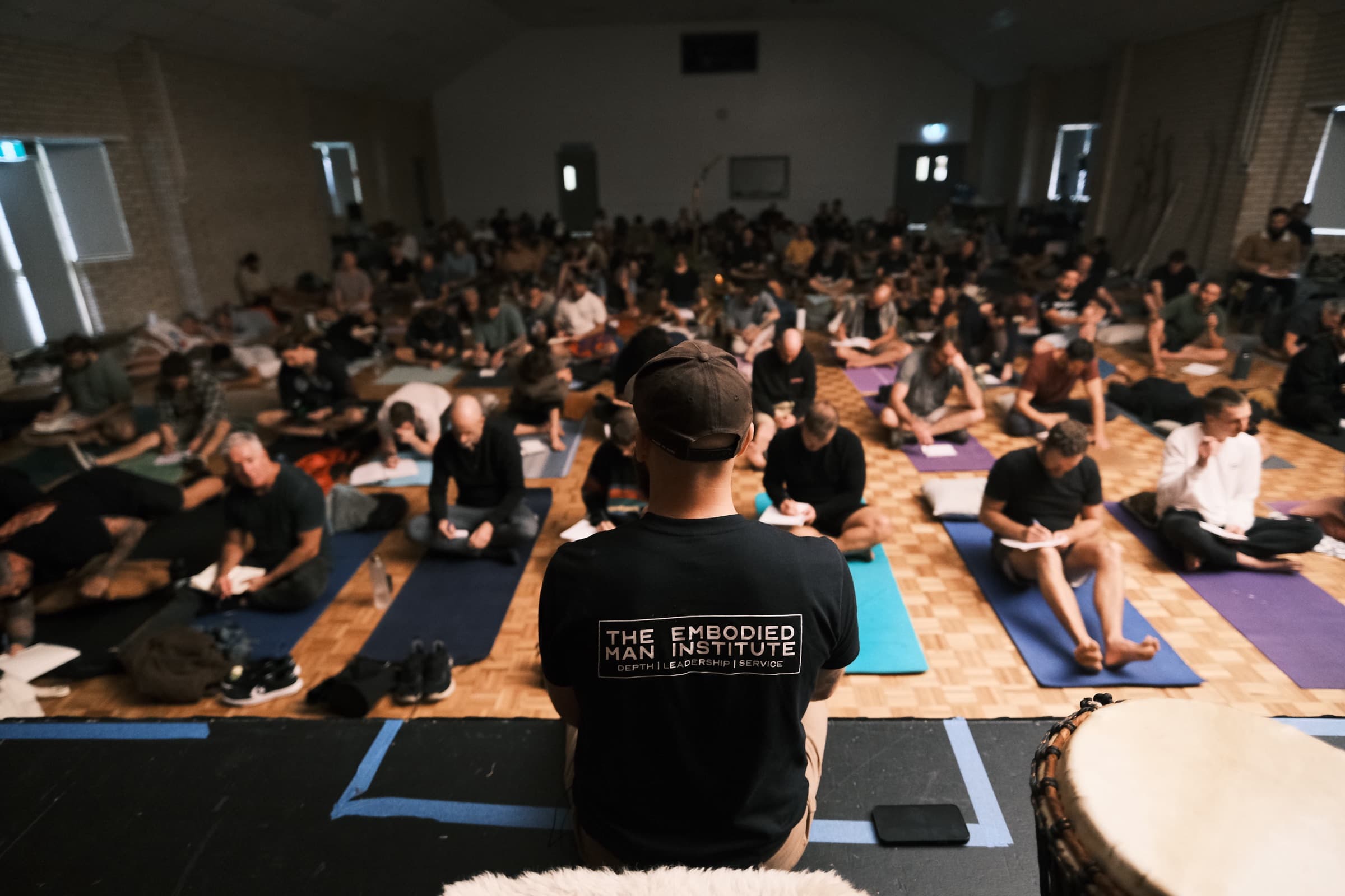 A hall of more than a hundred men seated for The Embodied Man Institute's work